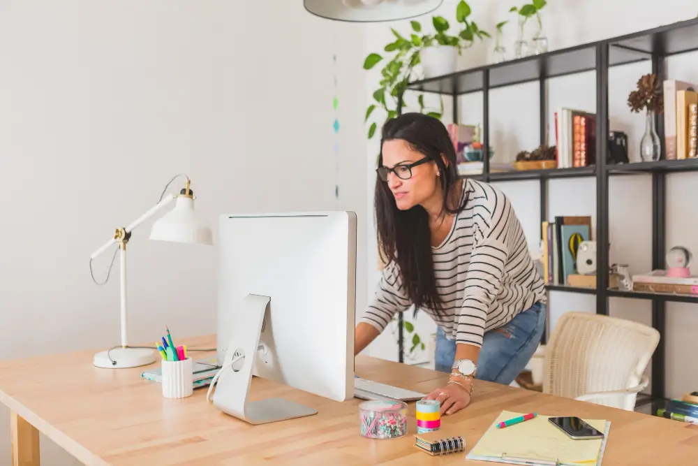 A woman focused on her computer while working in a home office environment.